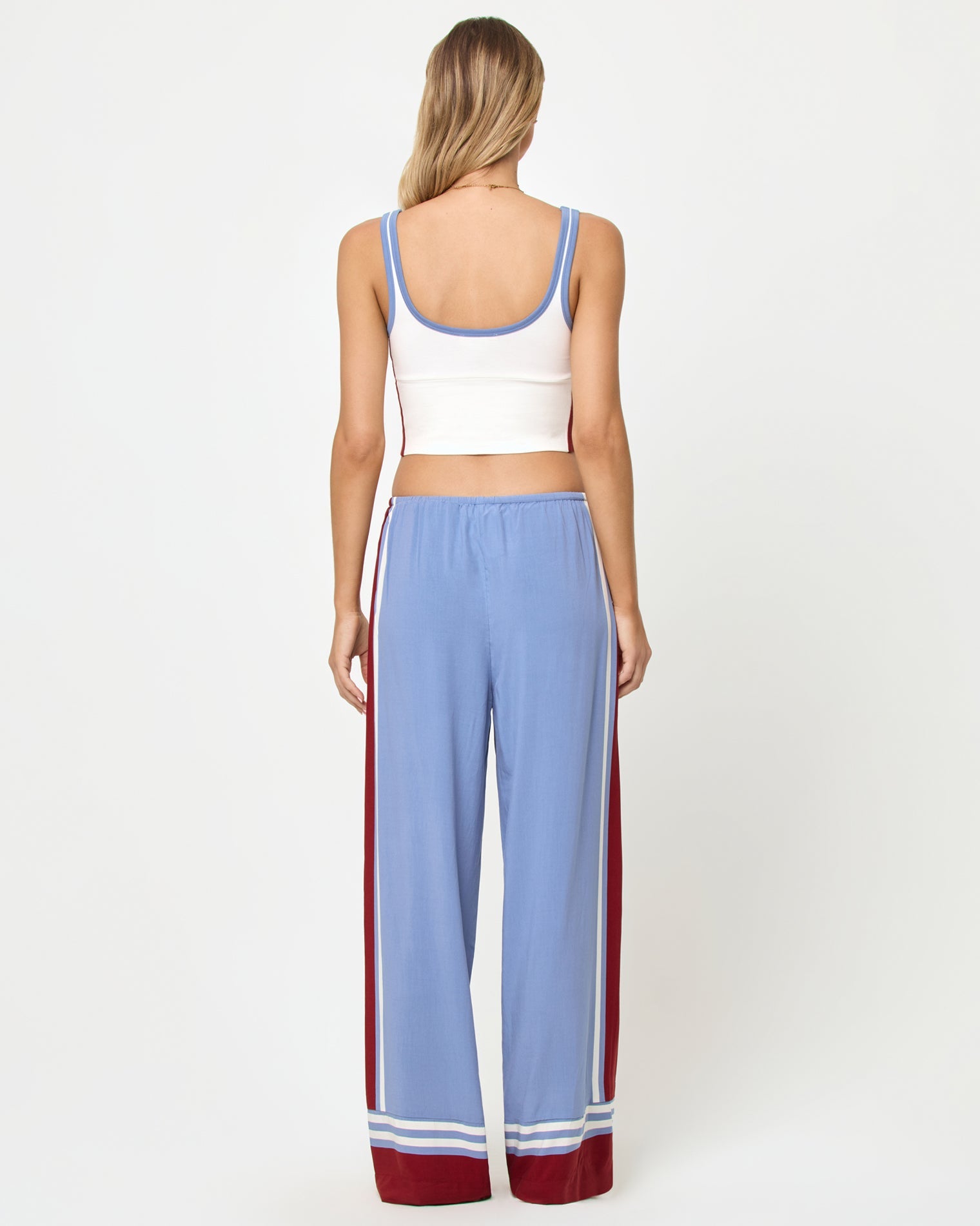 Back full-length studio view of the Reset Tank in Cream-Chambray-Fig, a cream ribbed scoop-neck crop cami with chambray blue strap trim and burgundy color-block side panels, styled with chambray blue wide-leg stripe pants with burgundy side stripes and stripe trim at the ankle hem.