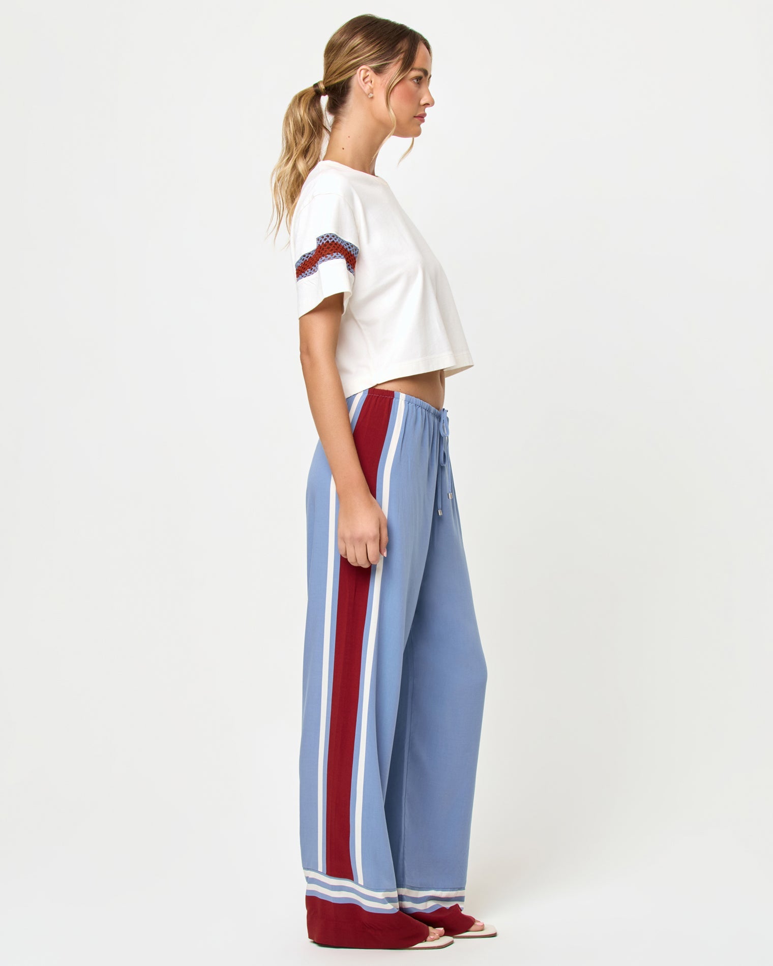 Side view of model wearing the LSPACE Unwind Pant in unwind stripe, a wide-leg pant with vertical stripe pattern.