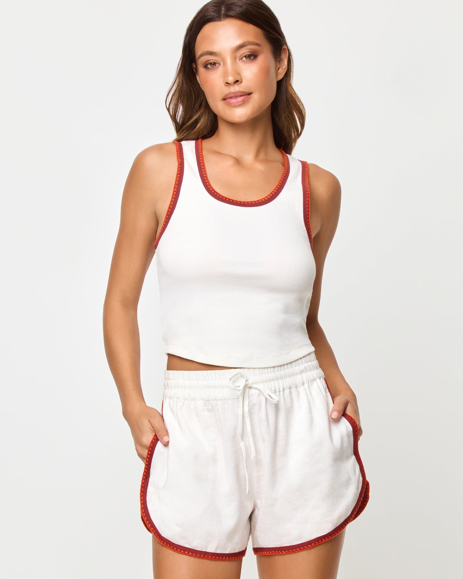 Cream Fig Poppy | Badge:New Arrival_#B2AC88_#ffffff'
Front studio torso view of the Ash Tank and Rune Short in Cream Fig Poppy, a cream ribbed scoop-neck crop tank with rust and terracotta crochet trim at the neckline and straps paired with matching cream runner shorts with the same crochet trim at the waistband and hem.
