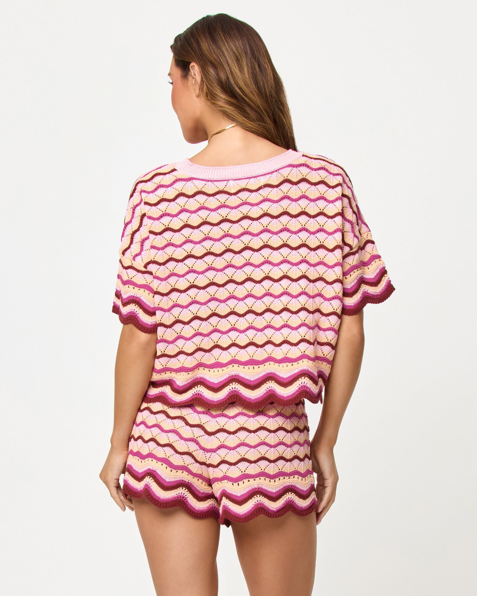 Back view of model wearing the LSPACE Sunchaser Top and Short in berry spritz, a crochet mini short with scalloped hem.